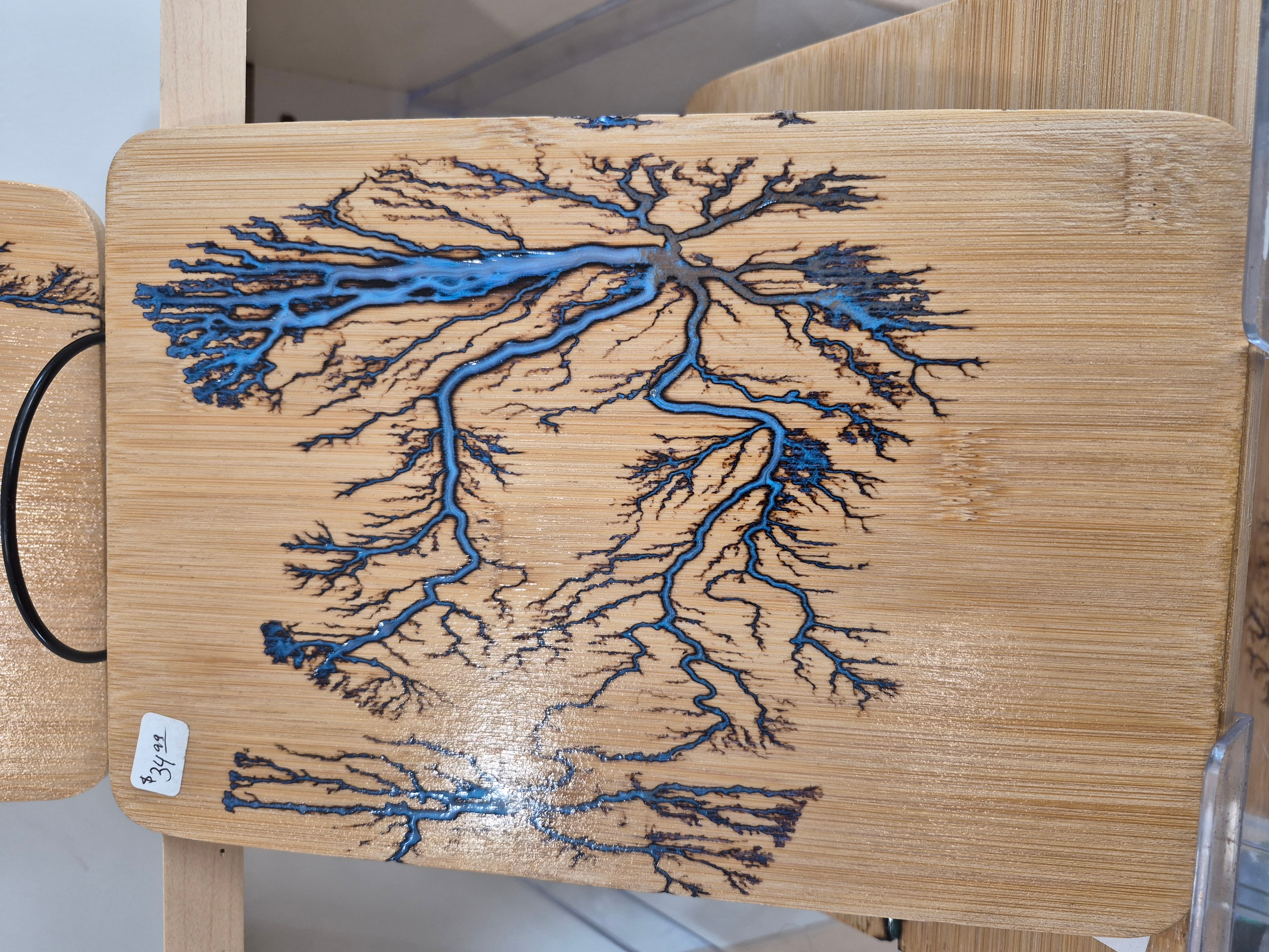 Wooden table with a blue and black tree-like pattern created with resin, resembling a branching tree or river system.