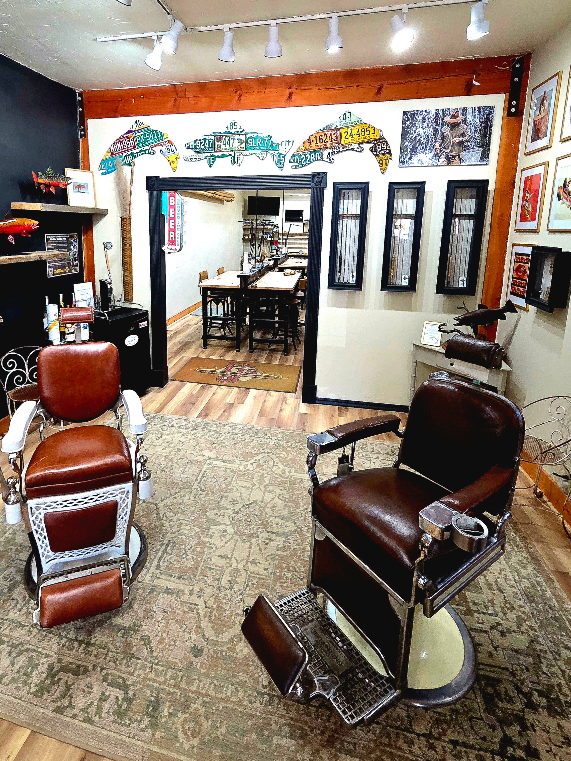 Barber shop interior with chairs, mirrors, and artwork on walls, viewed from the waiting area towards the back room.