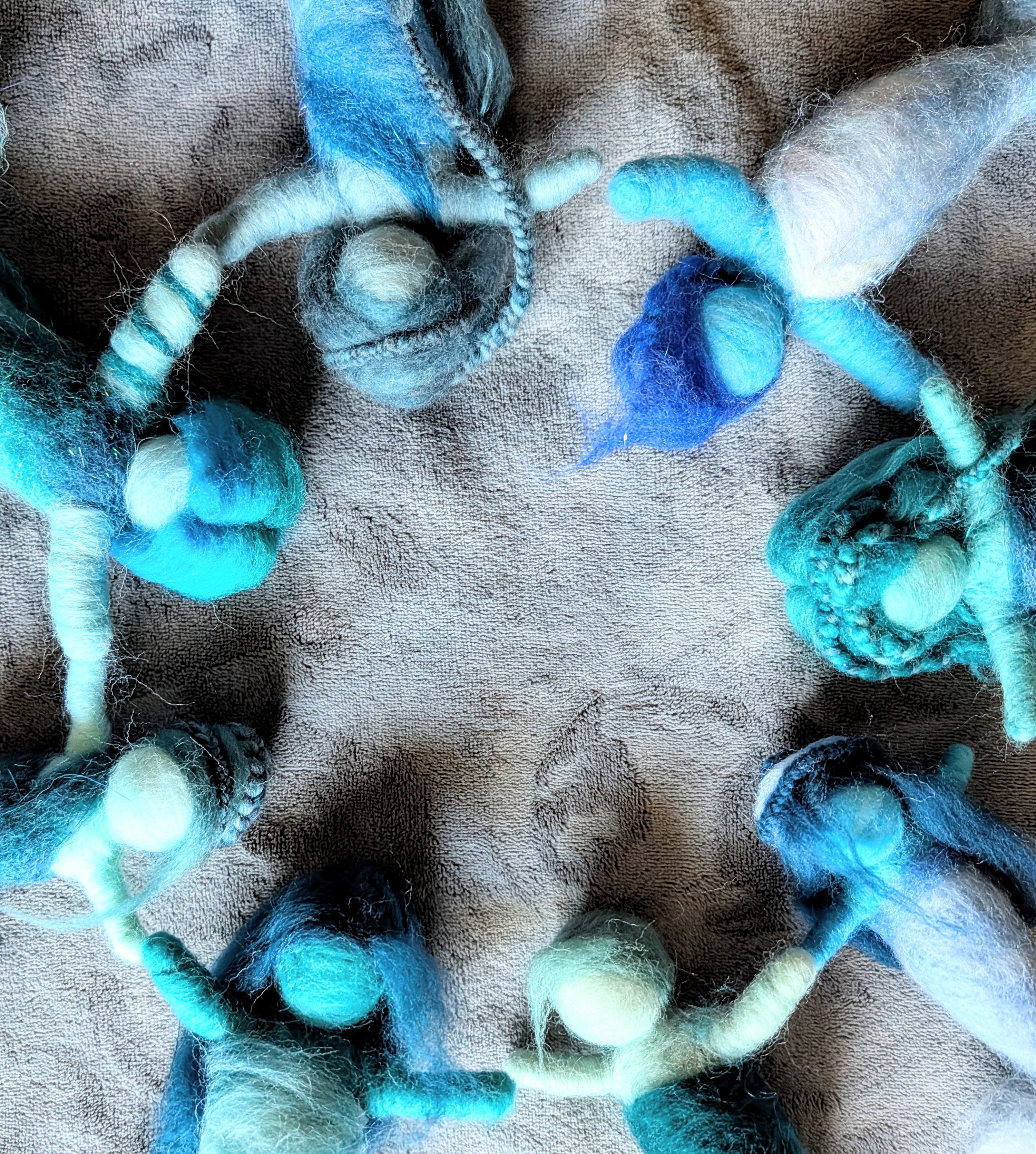Multiple skeins of blue, white, and gray yarn arranged in a circle on a soft surface.