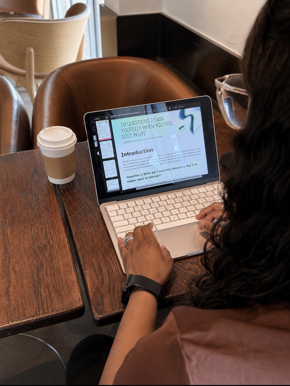 Person using a tablet with a presentation slide on a wooden table, with a coffee cup nearby, in a cafe setting.