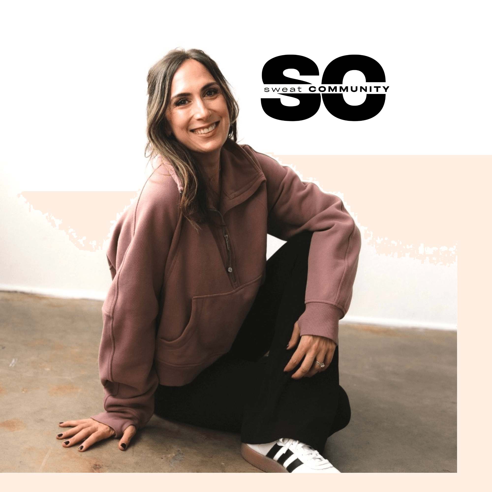 Young woman sitting on the floor, smiling, wearing a brown hoodie and black pants, with a logo in the background.