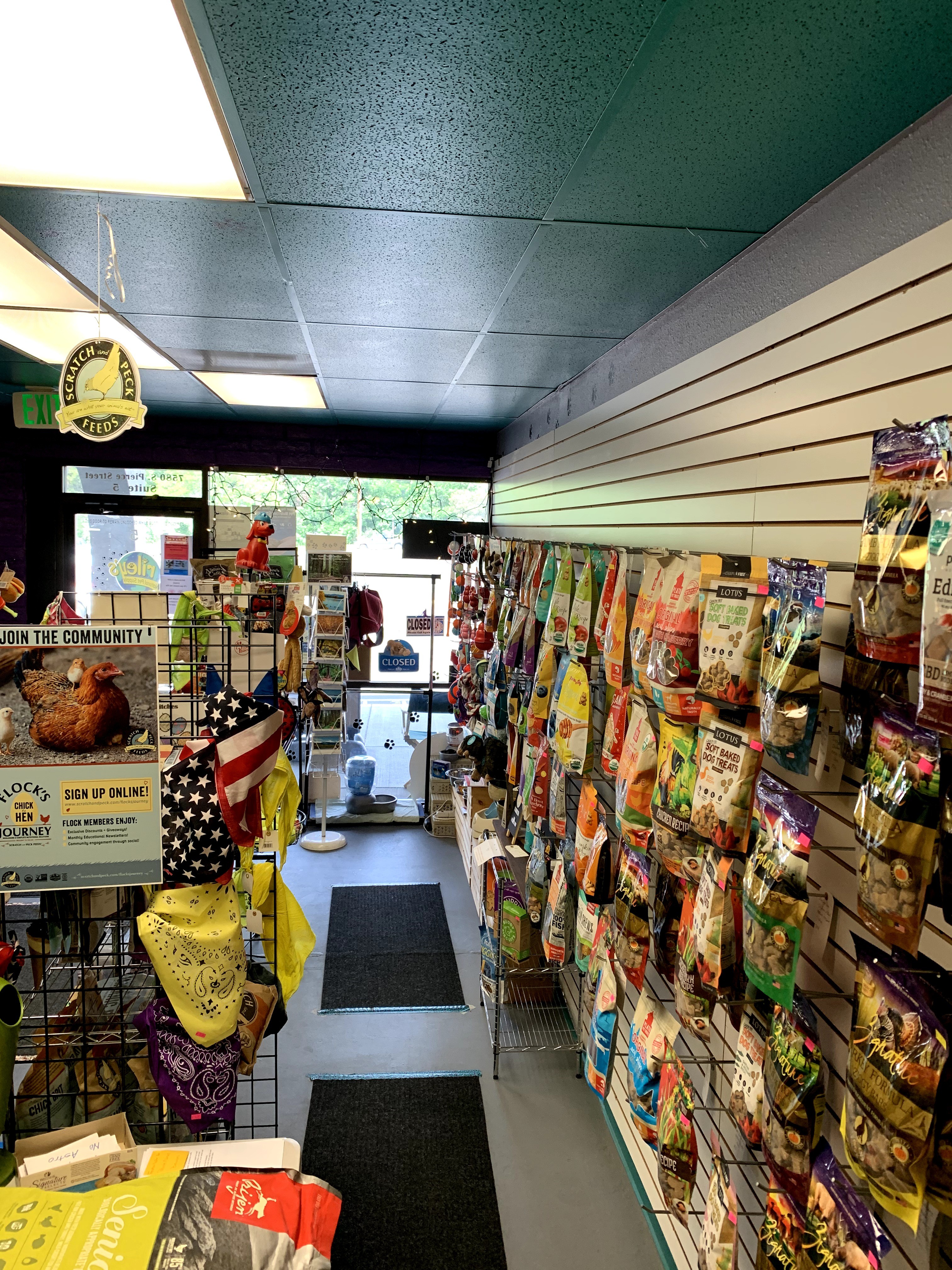 Inside a store with shelves stocked with snacks and colorful packaging, entrance door visible in the background, ceiling lights overhead.