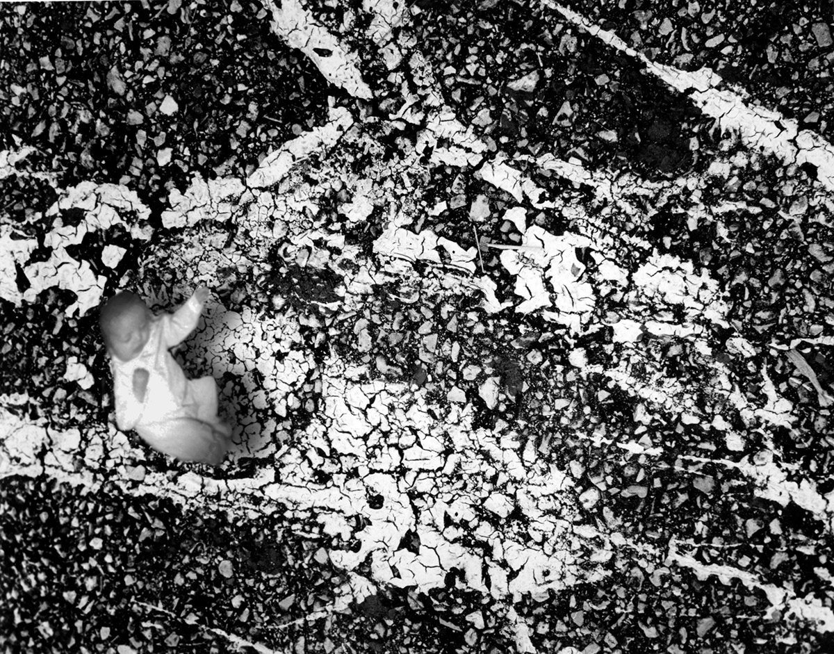 Person standing on cracked, textured ground with white markings, viewed from above.