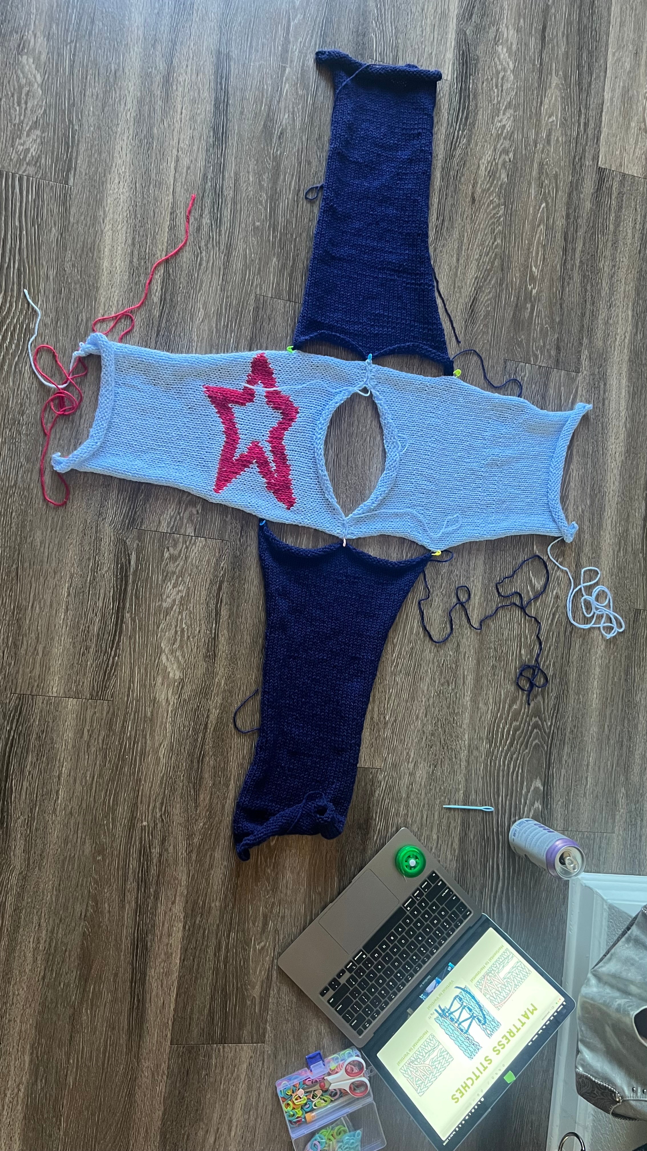 A handmade doll with a blue body, pink star, and dark blue arms and legs, lying on a wooden surface.