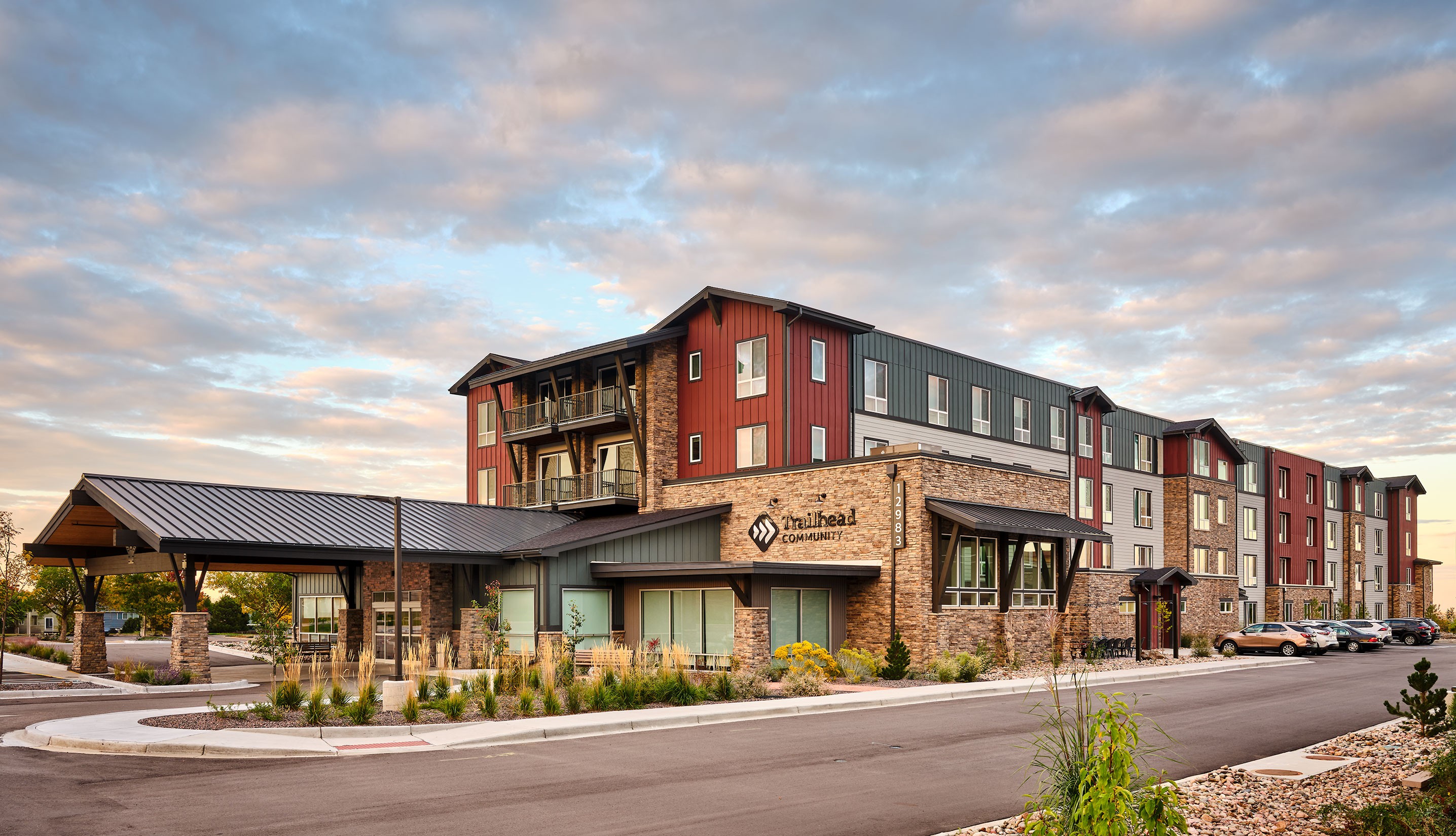 Multi-story hotel building with a stone and red exterior, under a partly cloudy sky, with a parking lot in front.