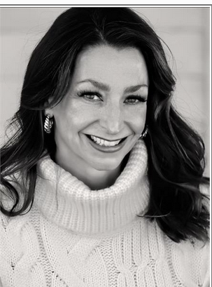 Woman with long dark hair smiling, wearing earrings and a turtleneck sweater, in black and white.