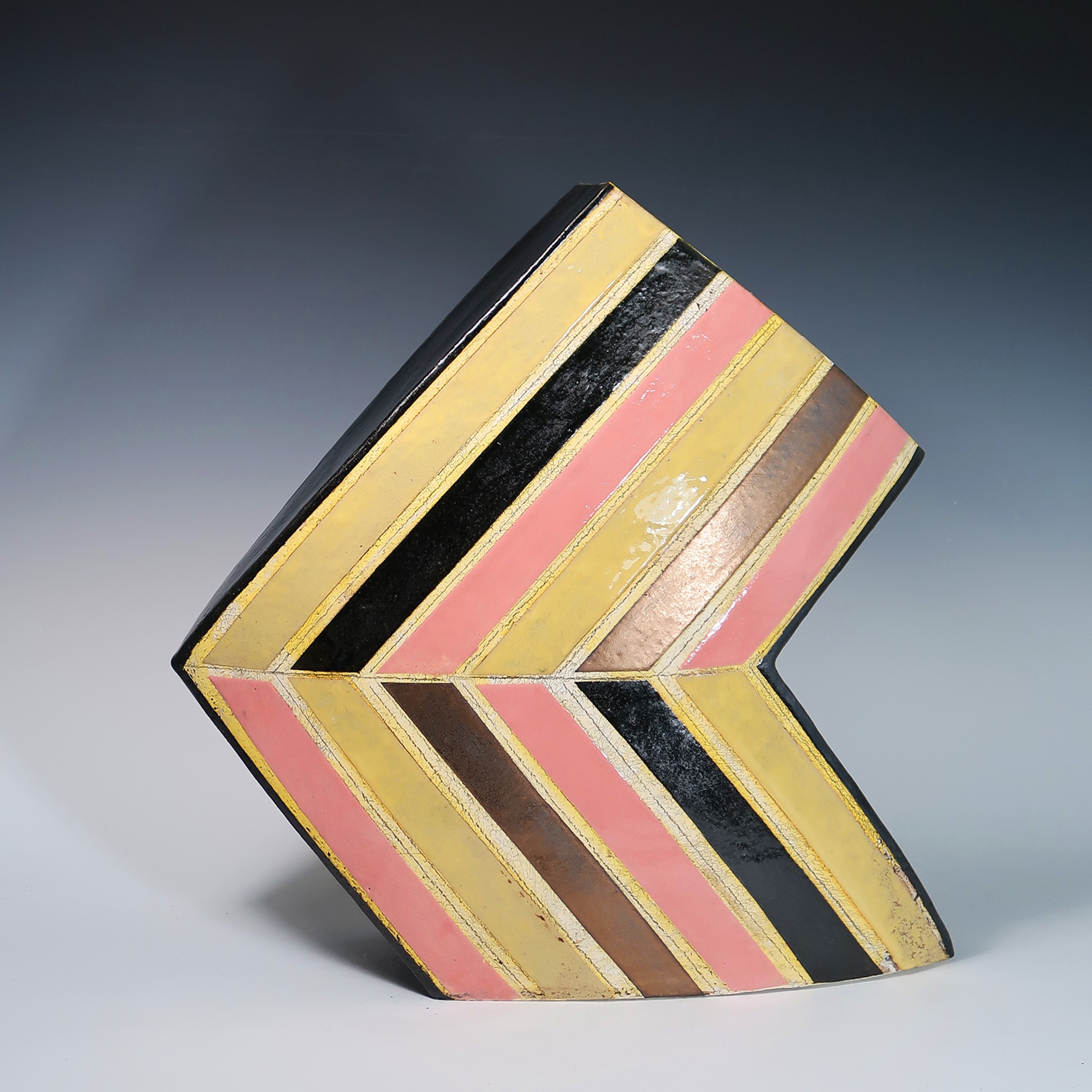 Colorful wooden block with pink, yellow, black, and brown stripes, shaped like a heart, on a gradient background.