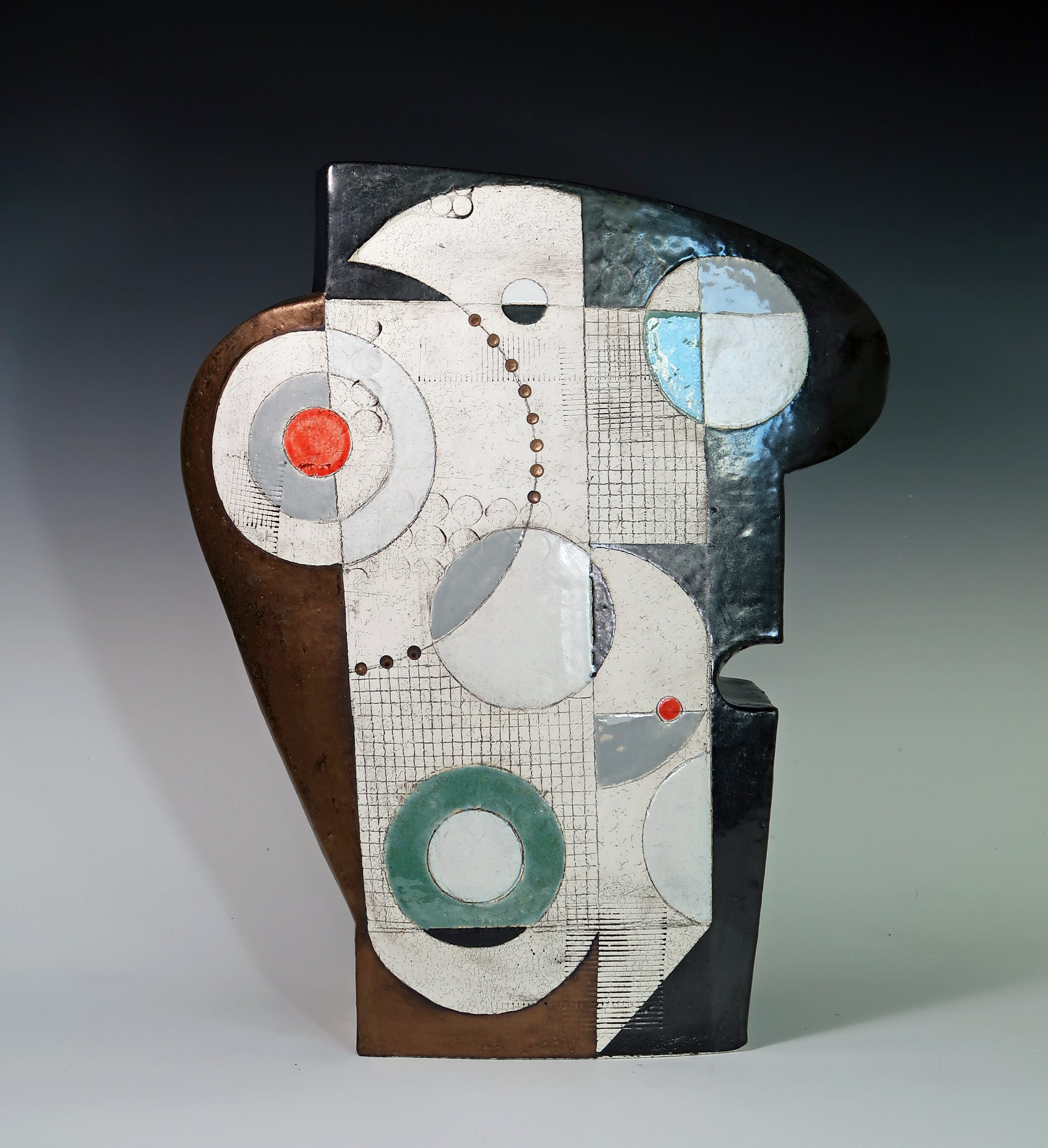 Abstract sculpture with geometric shapes and patterns, including circles, squares, and lines, in black, white, gray, blue, and red colors.