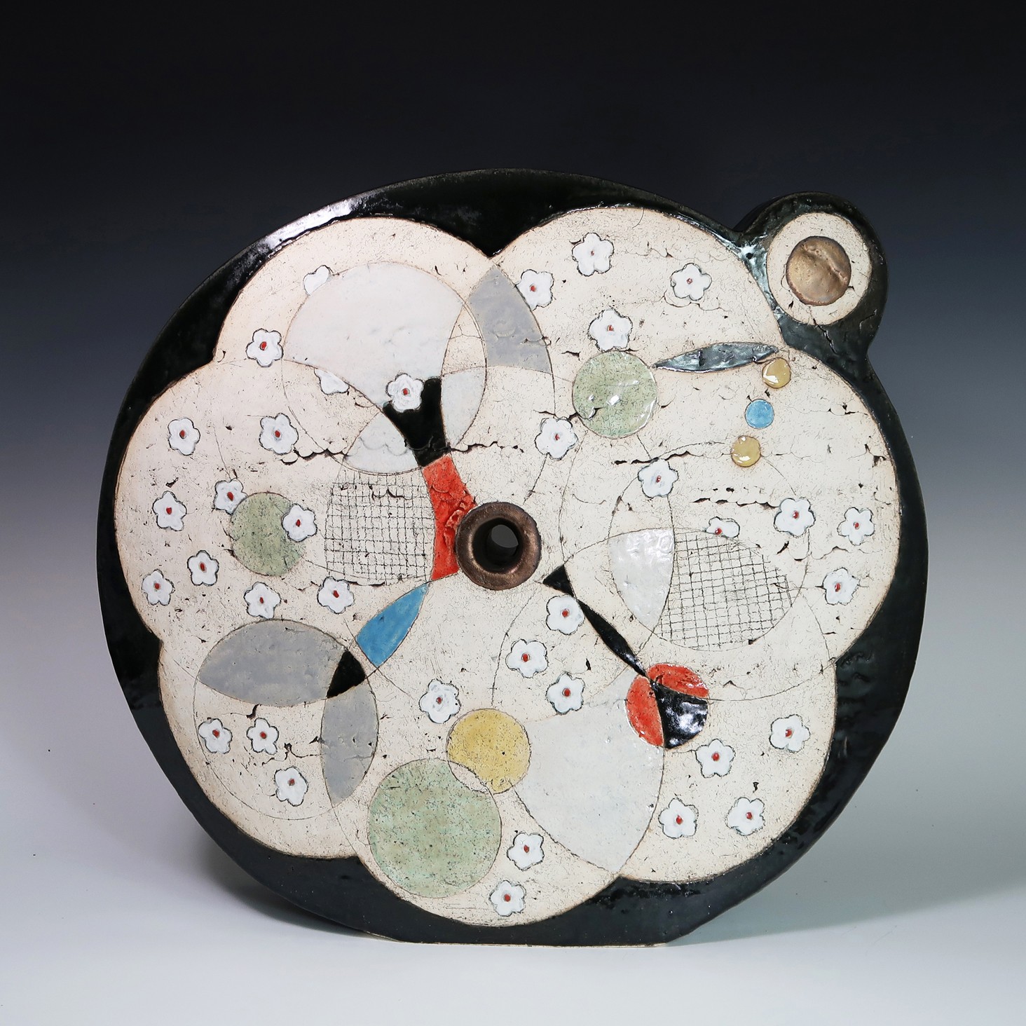 Round clock with floral design, black border, and two small protrusions on top right, showing time with black and red hands.