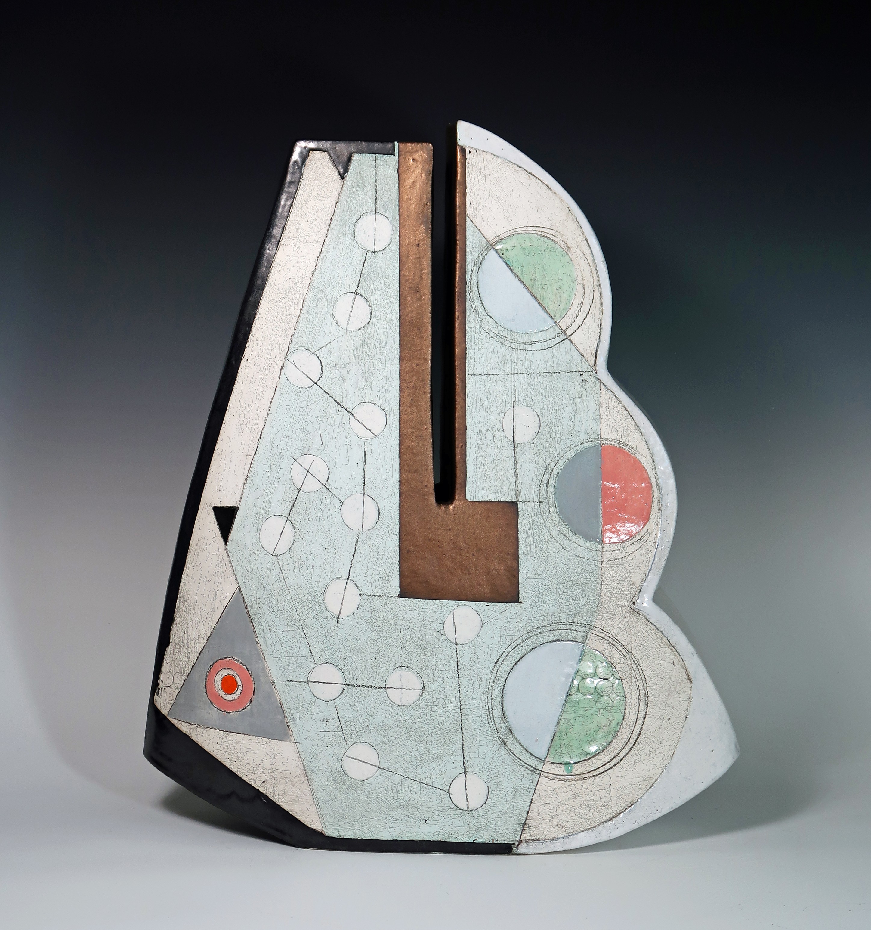 Abstract sculpture with geometric shapes and patterns, featuring circles, lines, and a central brown rectangle, against a dark background.