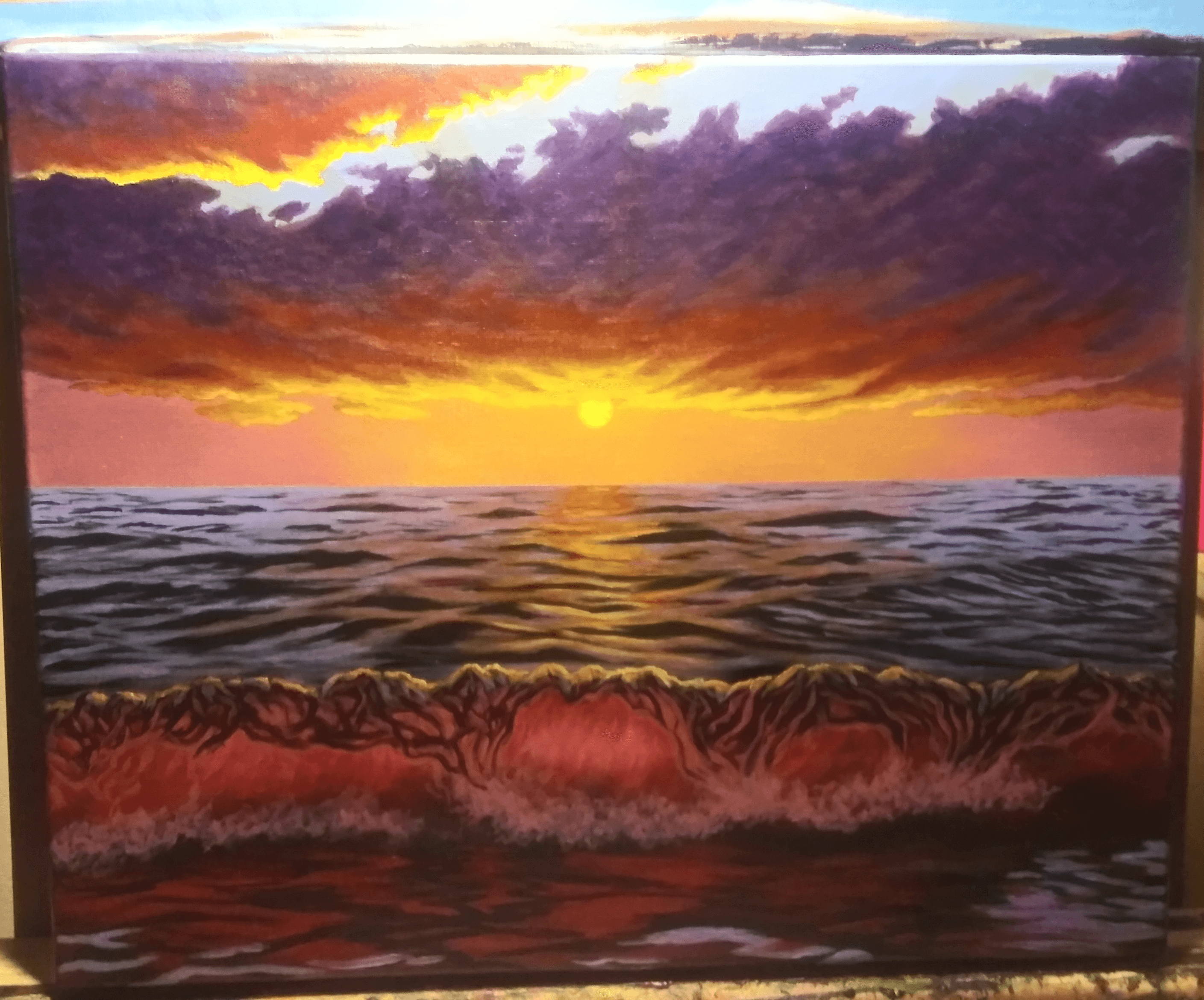 Sunset over the ocean with colorful clouds and waves, reflecting the sunset's glow.