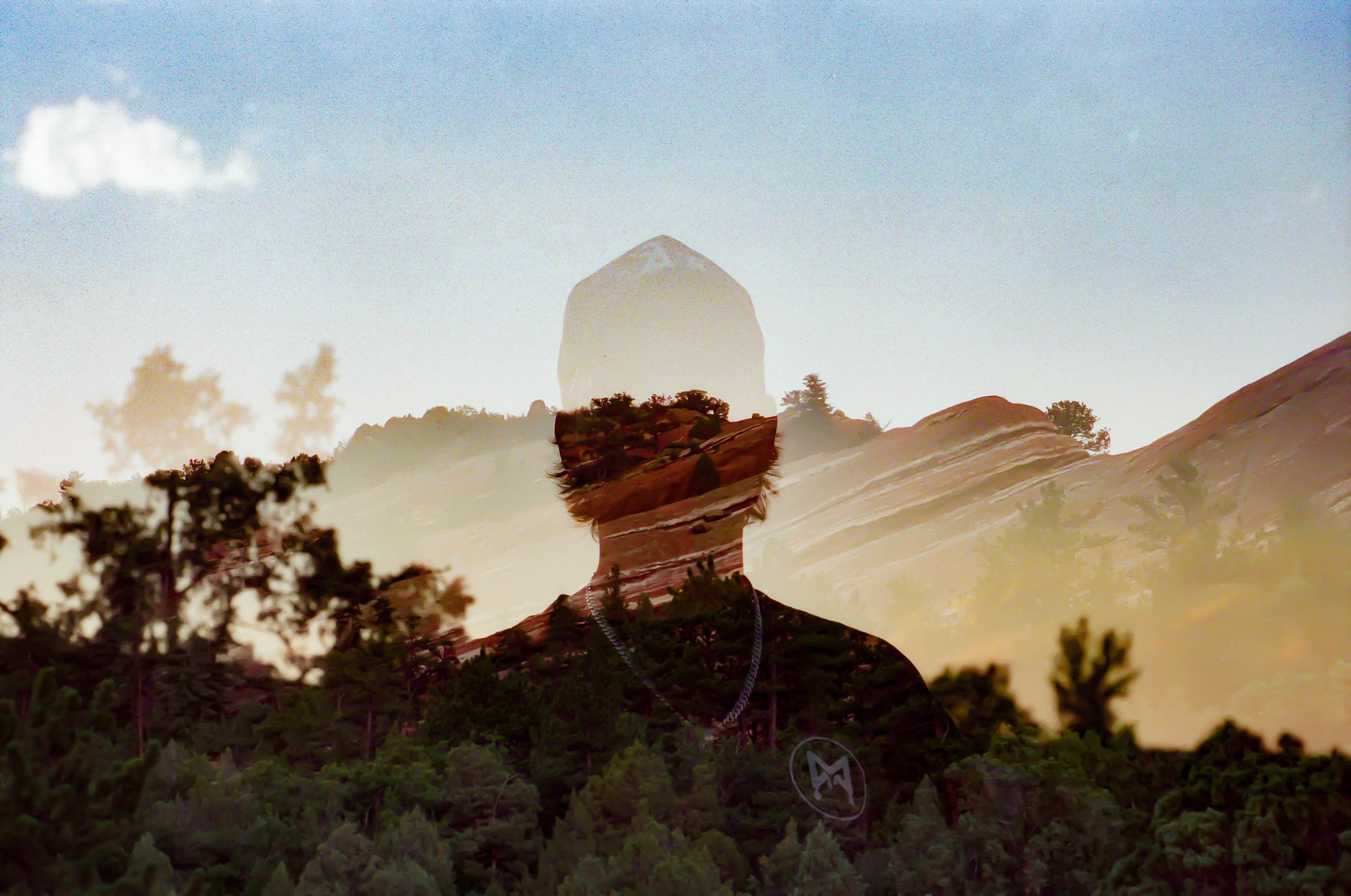 Double exposure of a person wearing a hat and a landscape with trees and mountains, blending together.