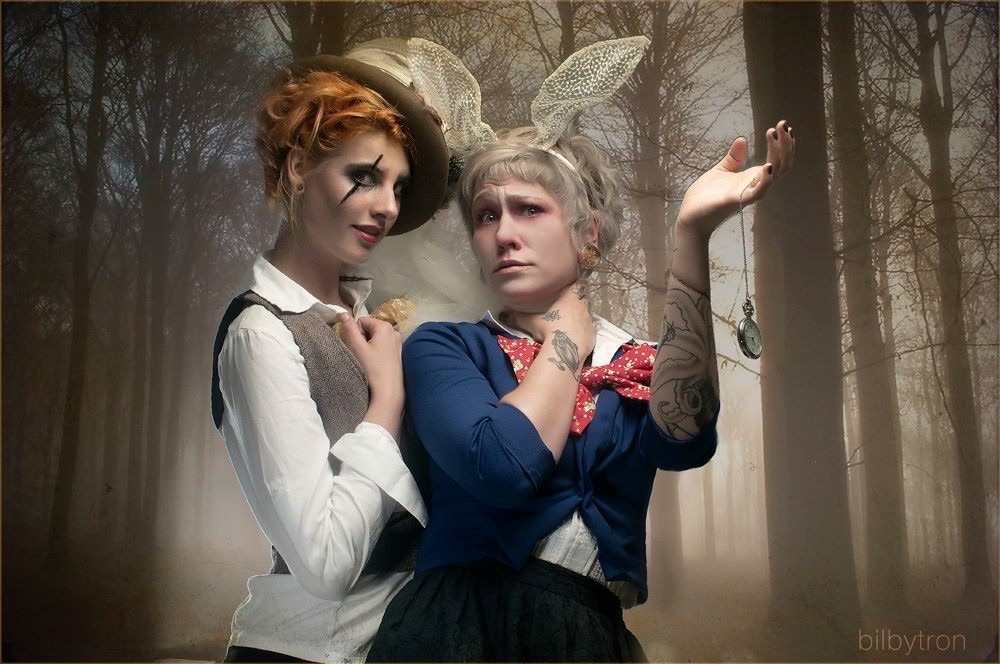 Two women in costumes with bunny ears pose in a foggy forest background.