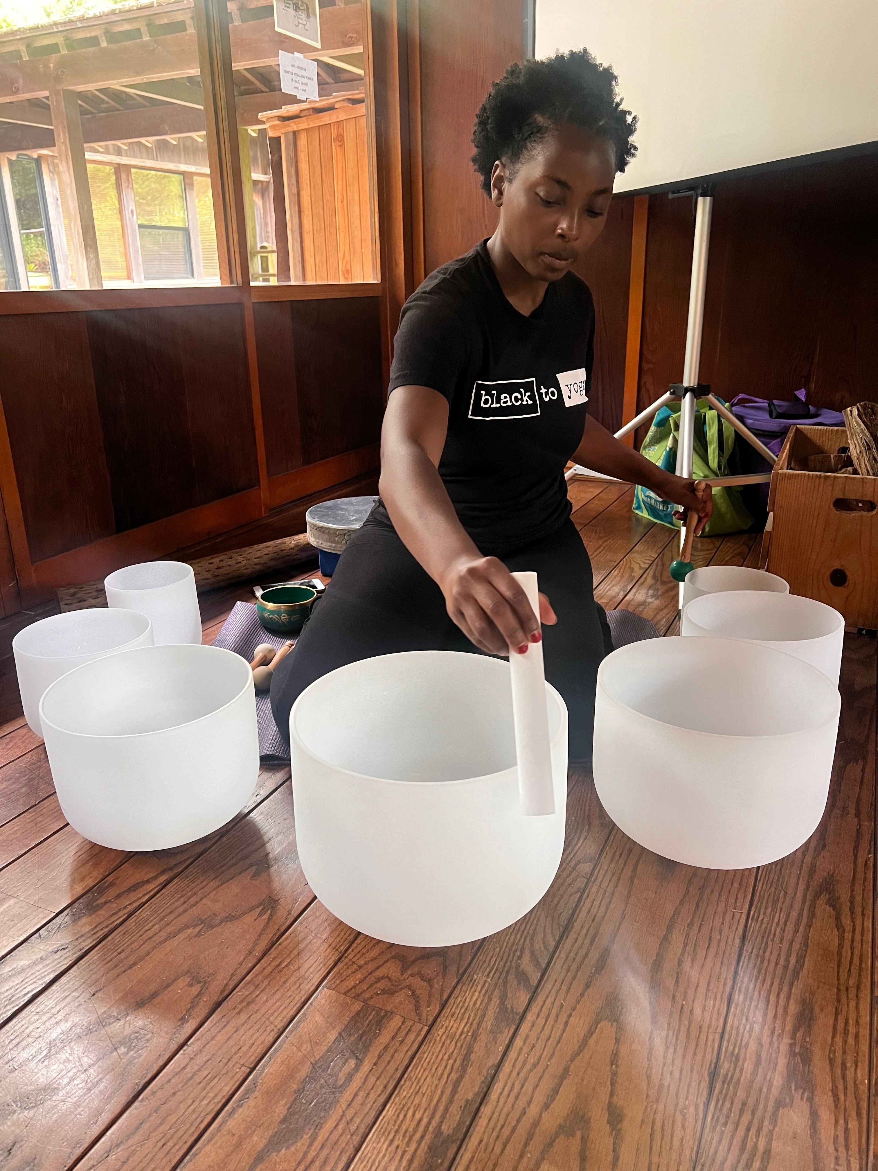 Person with curly hair and black shirt assembling white cylindrical objects on wooden table.