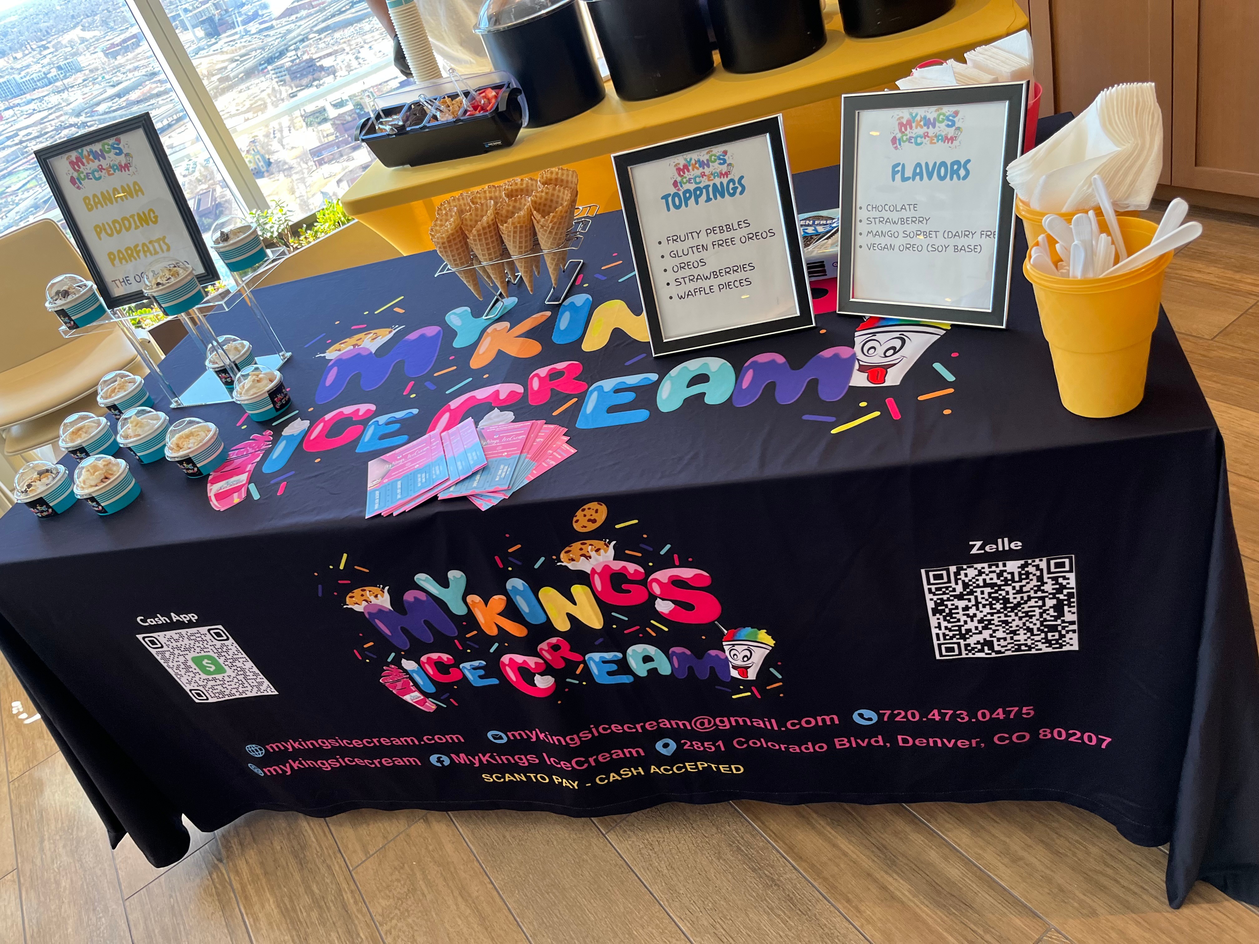 Ice cream themed display table with colorful letters, signs, and toppings, set indoors with sunlight streaming through windows.