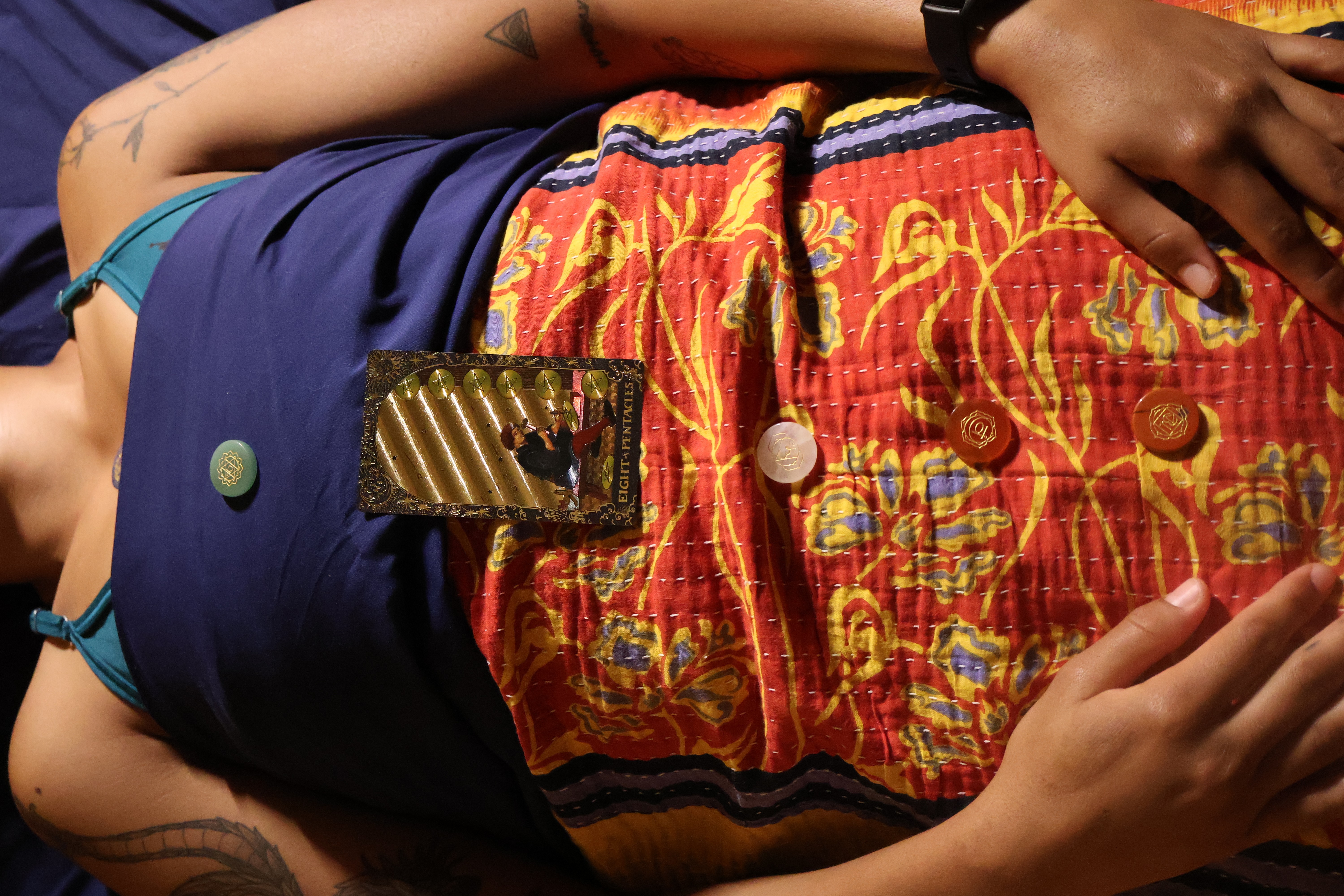 Person lying down wearing colorful shorts and a dark top, with a phone on their stomach.