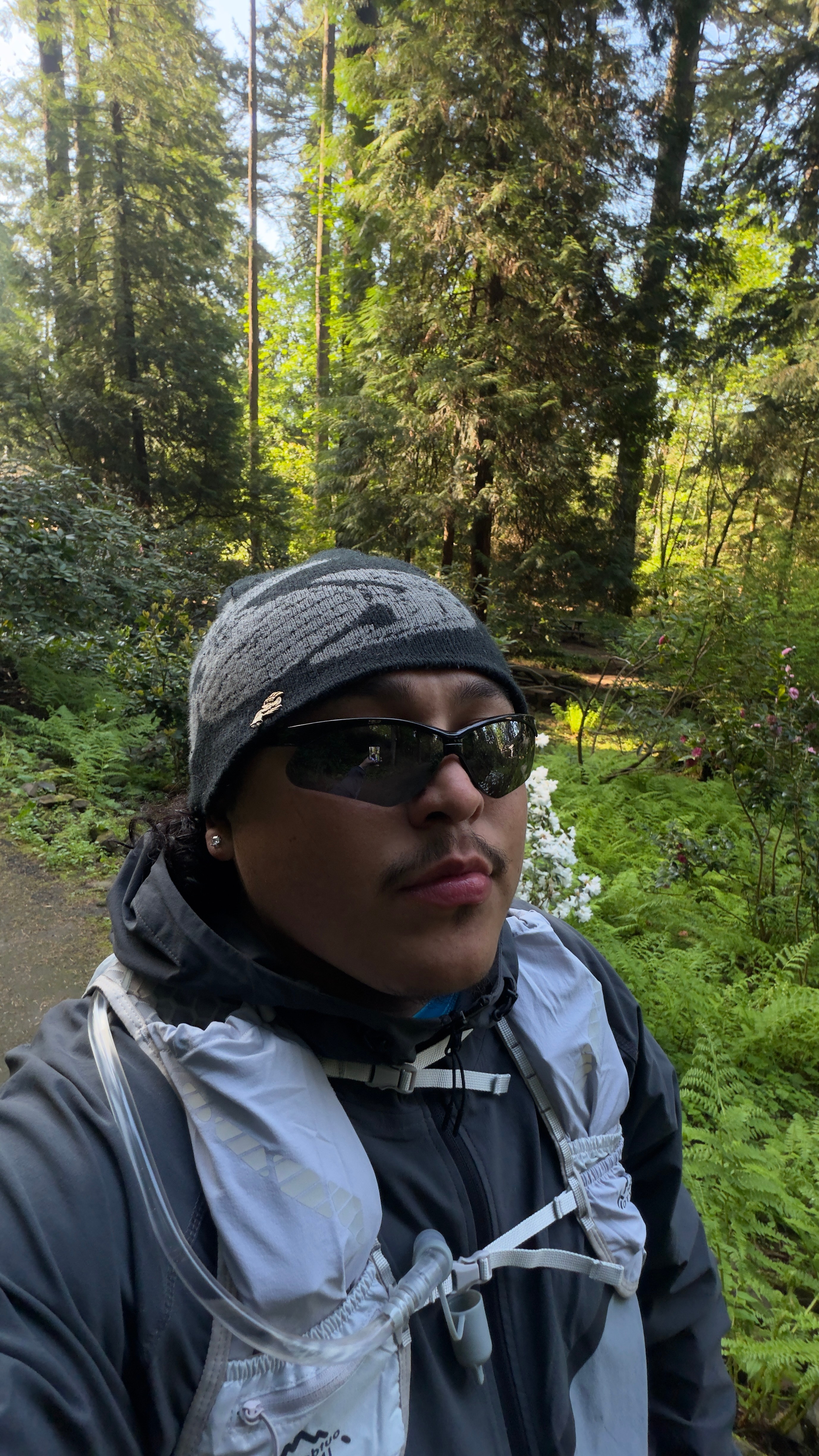 Person wearing sunglasses, a helmet, and a backpack outdoors in a forested area.