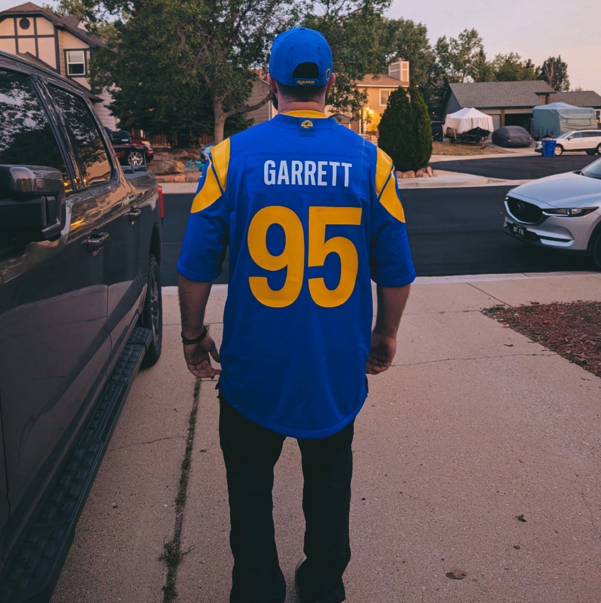 Person wearing a blue and yellow sports jersey with the name Garrett and number 95, walking on sidewalk.