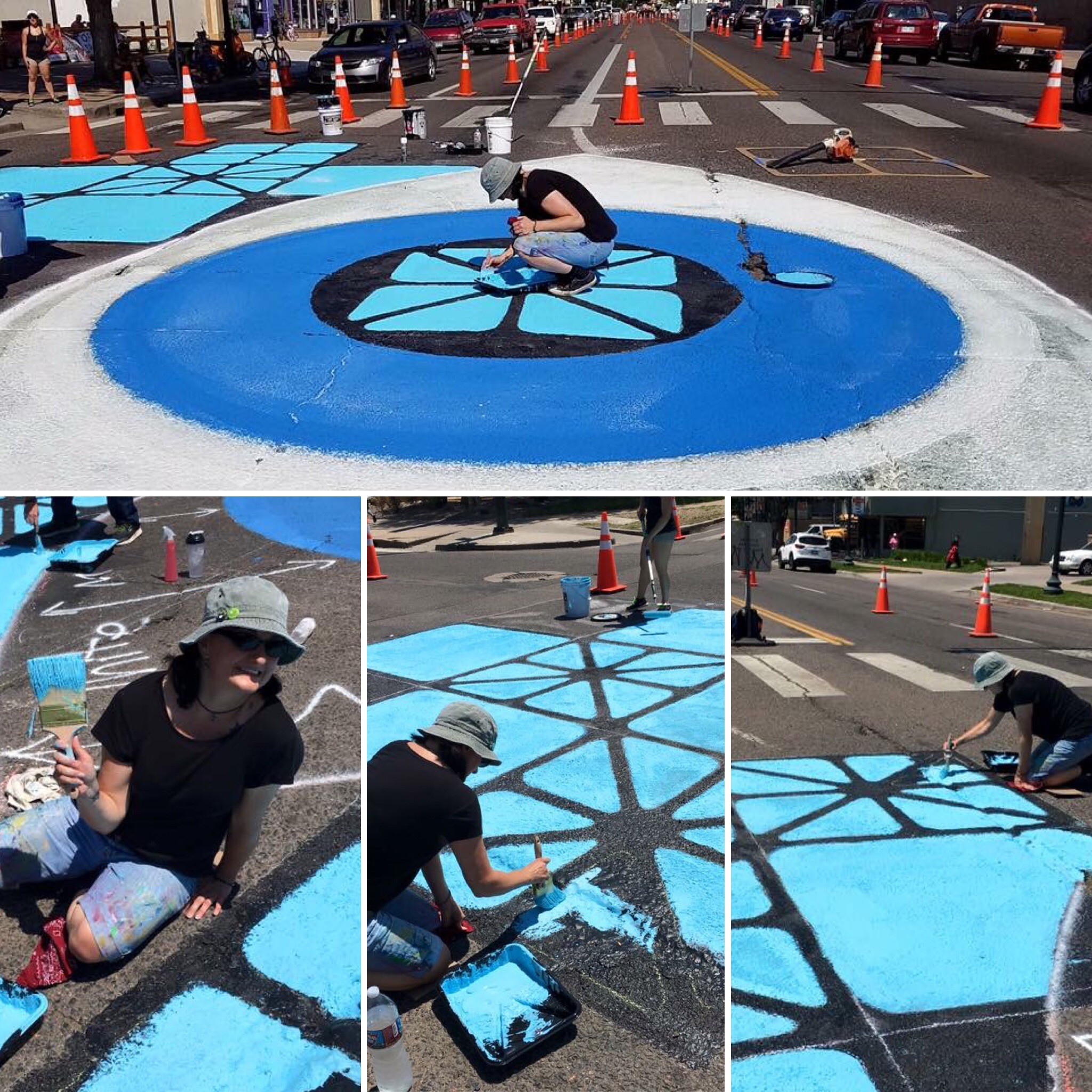 Person painting a large blue and black geometric design on the street with orange traffic cones around.