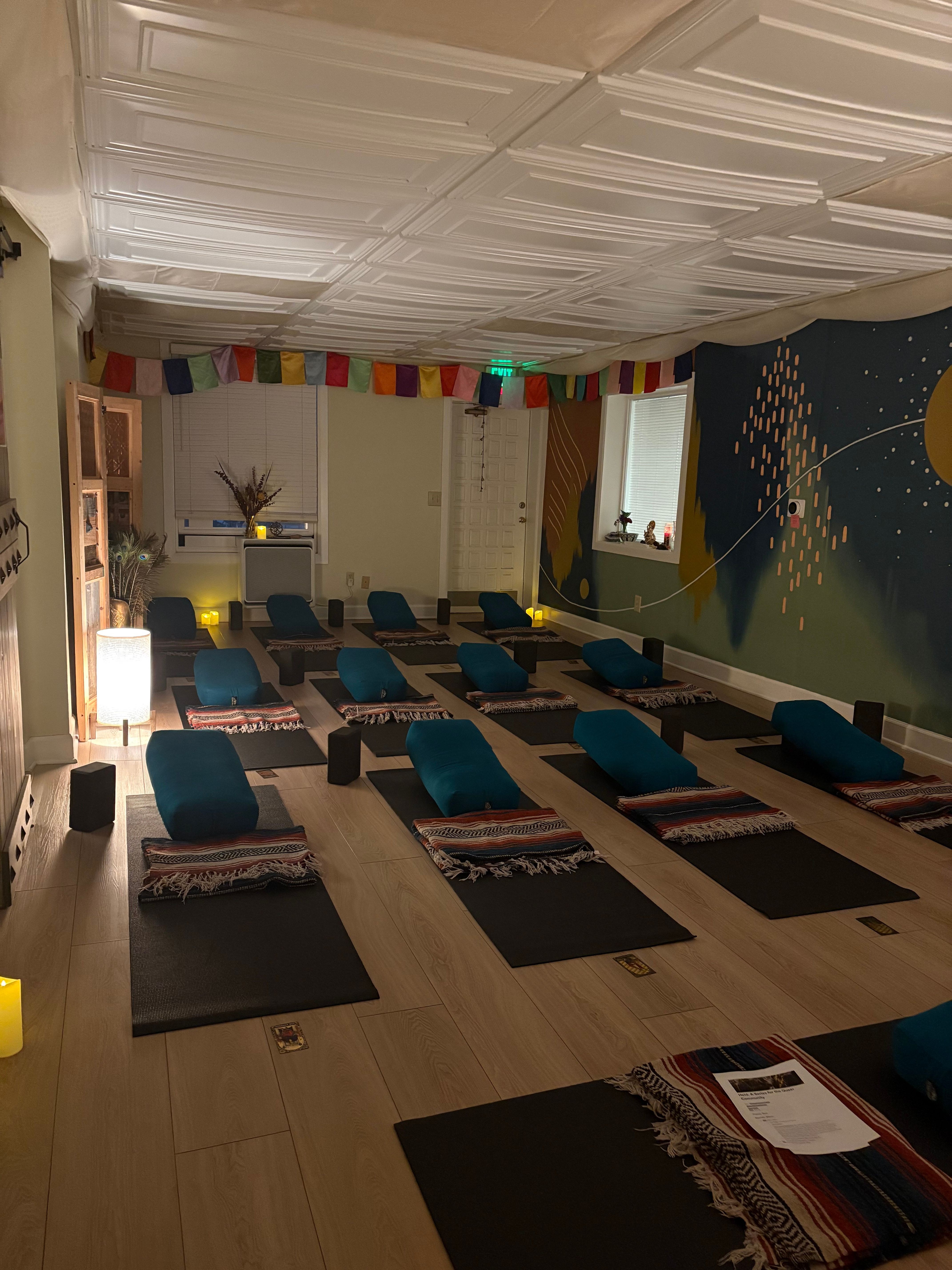 Room with a long table, blue chairs, colorful wall, and a mural with a moon and stars, lit by lamps.