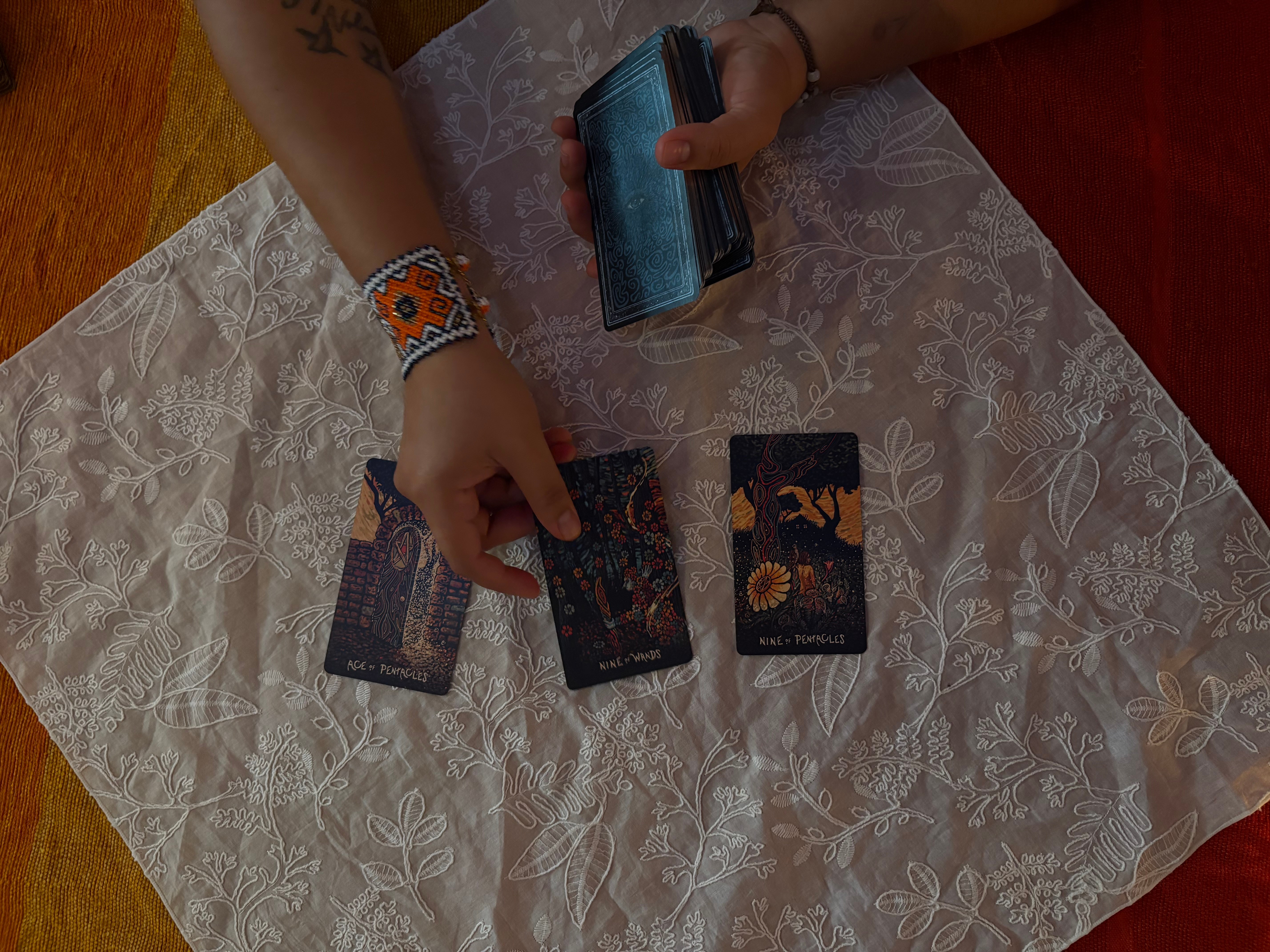 Person's hands holding a wallet and cards on a table with a lace tablecloth.