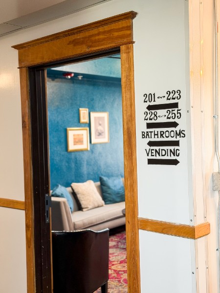 View through doorway into a room with blue walls, framed pictures, and a sofa with pillows.