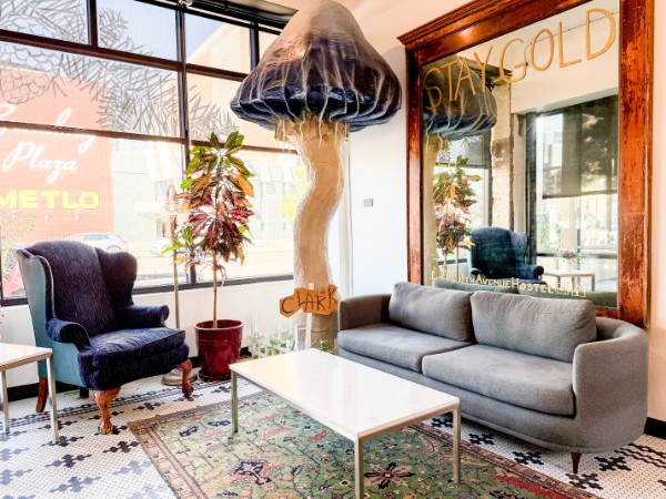 Living room with a gray sofa, a dark armchair, a white coffee table, and a large jellyfish sculpture in front of a window.