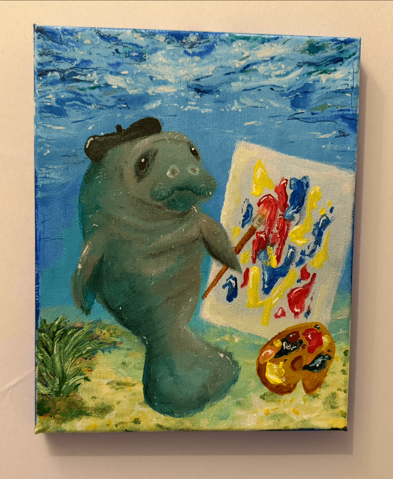 A creature with a fish body and a human face paints on a canvas outdoors, with a sky and greenery in the background.