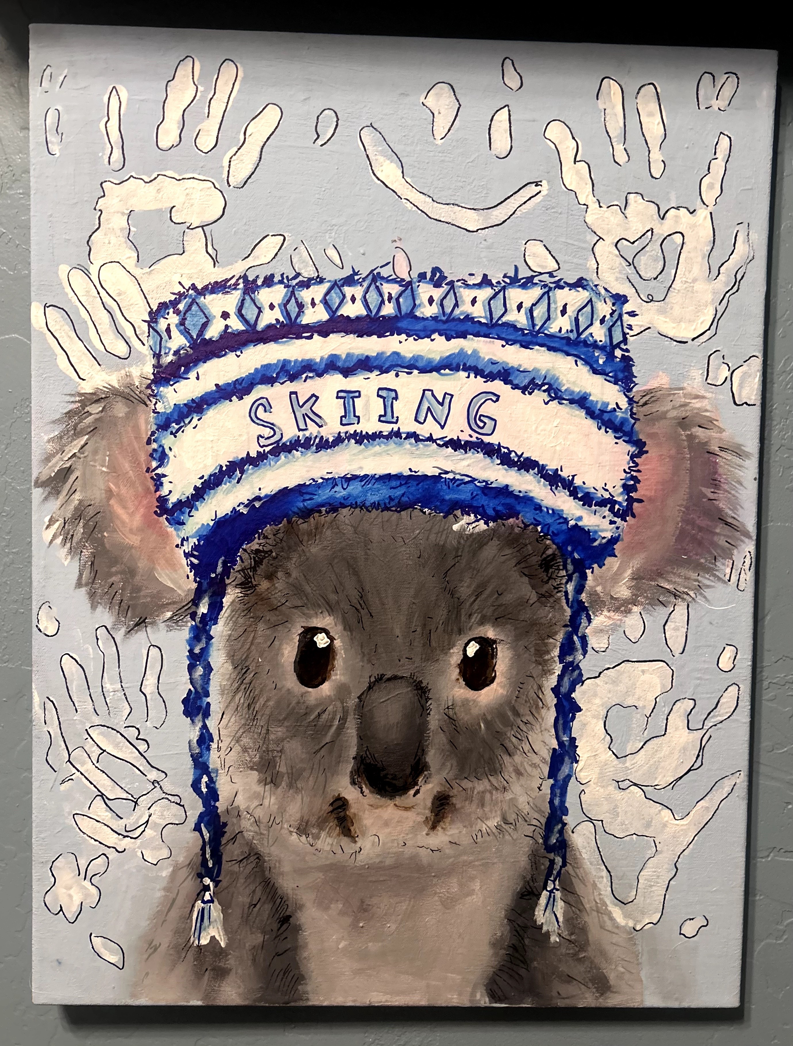 A puppy wearing a blue and white ski hat with the word 'SKIING' and ear flaps, surrounded by handprints.